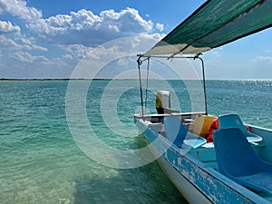 Blue-white boat moored on the beach by the azure sea near the town of Rio Lagartos, Yucatan, Mexico. Peaceful vacation