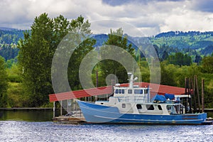 Blue and white boat sits docked along the Willamette River in Or