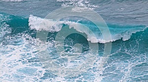 Blue and white breaking ocean wave seen from above