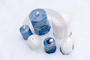 Blue and white candles flaming on snow