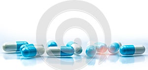 Blue and white capsules pill spread on white background with shadow and copy space. Global healthcare concept. Antibiotics drug