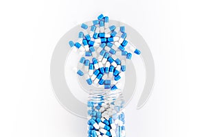 Blue and white capsules poured from a bottle - sports supplement creatine - on white background top view