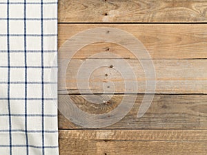Blue and white checkered dishcloth on brown rustic wooden plank table flat lay top view from above