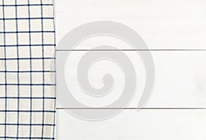 Blue and white checkered dishcloth on white wooden plank table flat lay top view from above