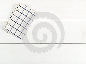 Blue and white checkered dishcloth on white wooden plank table flat lay top view from above