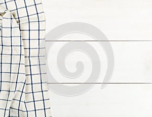 Blue and white checkered dishcloth on white wooden plank table flat lay top view from above