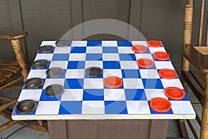 A blue and white checkers board with black and red game pieces, set up and ready for action, Lancaster County