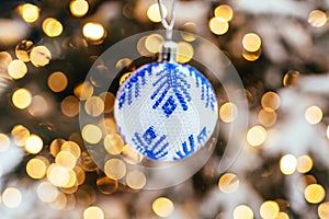 Blue white christmas ball on fir tree branch close up golden yellow light bokeh