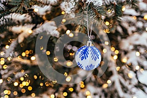 Blue white christmas ball on fir tree branch close up golden yellow light bokeh