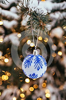 Blue white christmas ball on fir tree branch close up golden yellow light bokeh