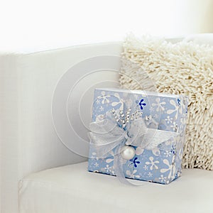 Blue and white Christmas gift present in modern living room home interior with white background. Selective focus on gift