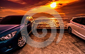 Blue and white compact SUV car with sport and modern design parked on concrete road by the sea at sunset. Environmentally friendly