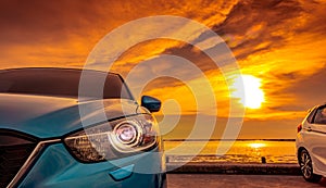 Blue and white compact SUV car with sport and modern design parked on concrete road by the sea at sunset. Environmentally friendly