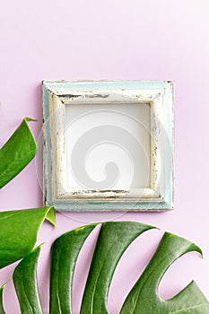 Blue and white empty photo frame and tropical leaves mockup on purple background. Travel concept. Text