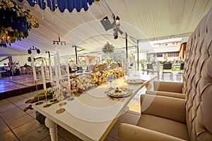 Blue, white and gold Wedding table dining set decoration over white tablecloth, golden and white plates with floral arrengement