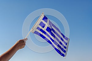 Hand waving Greek flag in the air for a national celebration. photo
