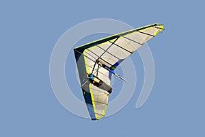 Blue and white hang glider in flight off,isolated on light blue