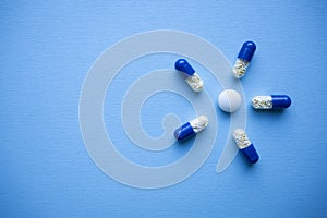 Blue and white medical pills on a blue  paper background in the form of a flower top view with copy space