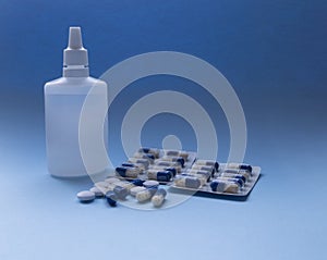 Blue and white medical pills and liquid medicine in plastic bottle on a blue background