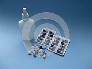 Blue and white medical pills and liquid medicine in plastic bottle on a blue paper background