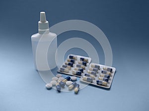 Blue and white medical pills and liquid medicine in plastic bottle on a blue paper background