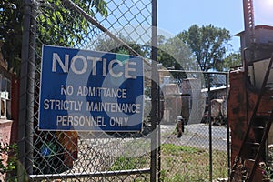 Blue and white Notice, No Admittance, Strictly Maintenance Personnel Only warning sign on the fence of an industrial site