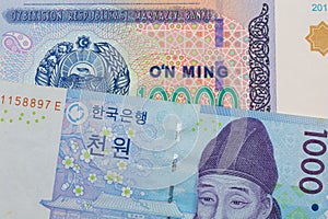 A blue and white one thousand won bill from Korea paired with a blue, white and green ten thousand som note from Uzbekistan.