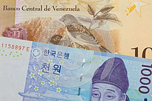 A blue and white one thousand won bill from Korea paired with a colorful one hundred Bolivar bank note from Venezuela.