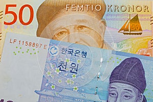 A blue and white one thousand won bill from Korea paired with a gray and orange fifty kronor note from Sweden.