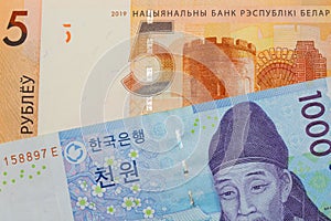 A blue and white one thousand won bill from Korea paired with a orange five ruble bank note from Belarus.