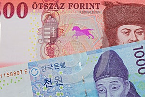 A blue and white one thousand won bill from Korea paired with a red and white five hundred forint note from Hungary.
