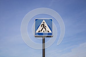 Blue and white pedestrian crossing sign on the sky background