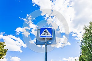 Blue and white pedestrian crossing sign on the sky background