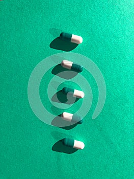 Blue and white pills on green background