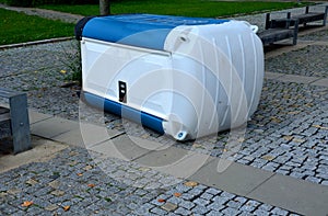 blue white plastic mobile toilet lying on its side photo