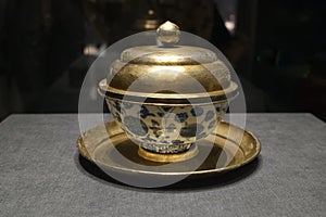 A blue and white porcelain bowl with a gold cover and gold stand, made in the Ming Dynasty