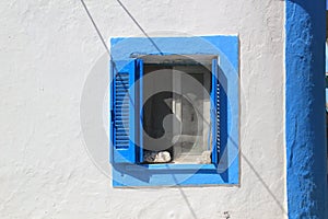 Blue and white shuttered window in wall on Greek Island