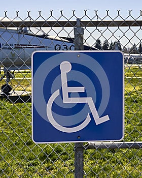 Blue and white sign with symbol of a person in a wheelchair indicating a park is wheelchair friendly