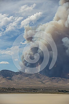 Blue and white sky puffy cumulonimbus clouds and smoke from a large wildfire in the desert