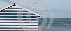 Blue and white striped beach hut with sea views and wind farm