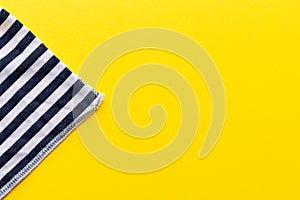 Blue and white striped fabric closeup triangle on a bright yellow background. Top view with copy space. Summer concept template