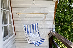 Blue and white striped pattern string and cotton hammock hanging chair, white painted wooden board background