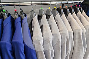 Blue and white suits hanging on the wooden clothes hanger of man cloth store with a cosy and businessman style. Official men wear