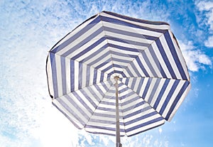 Blue and white sun beach umbrella and blue sky with clouds