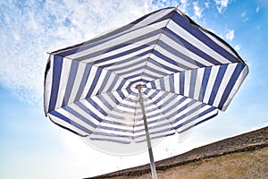 Blue and white sun beach umbrella and blue sky with clouds