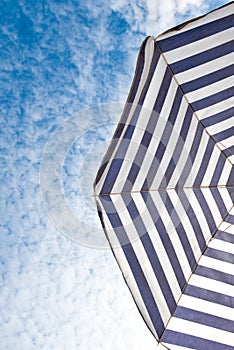 Blue and white sun beach umbrella and blue sky with clouds