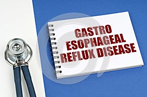 On a blue-white surface lies a stethoscope and a notepad with the inscription - Gastro Esophageal Reflux Disease