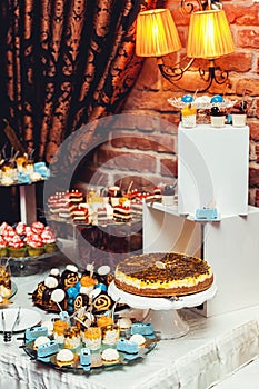 Blue white sweets on gilded paper on the wedding candybar. Brick wall on a background