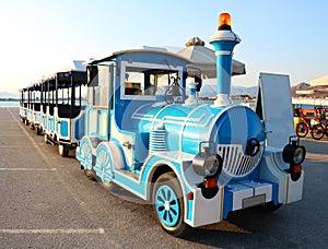 Blue and white tourist excursion locomotive on sea beach in Greece