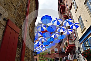 Blue and white umbrella suspended over an old Quebec city street